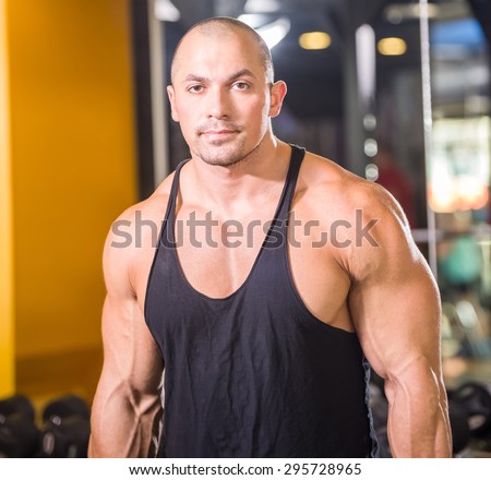 Muscular and fit young bodybuilder posing at gym.