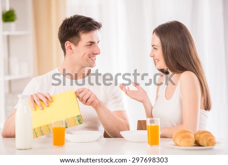 Young family couple sitting at the table in the kitchen and preparing breakfast together.