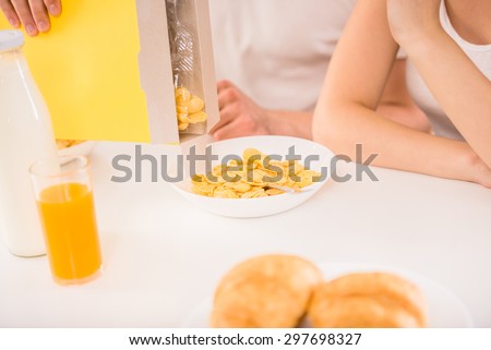 Young family couple sitting at the table in the kitchen and preparing breakfast together. Close-up.