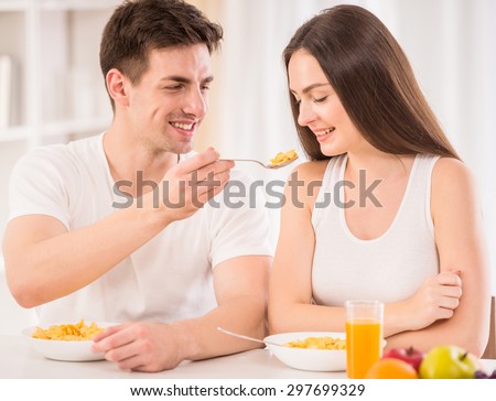 Cute couple having breakfast together. Man feeding his girlfriend with corn flakes.