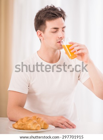Portrait of young man drinking juice in the kitchen.