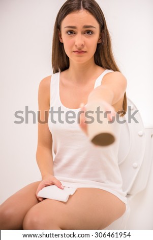 Sad woman holding an empty toilet paper roll isolated on white background