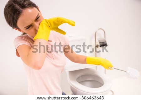 Woman with a rubber glove cleans a toilet bowl using means for cleaning