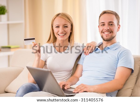 Online Shopping. Happy smiling couple using credit card to internet shop on-line.