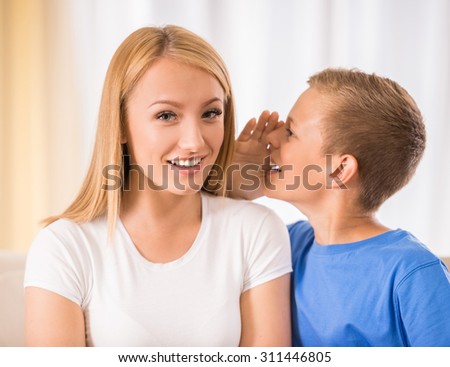 Teen son is whispering something to his mother.