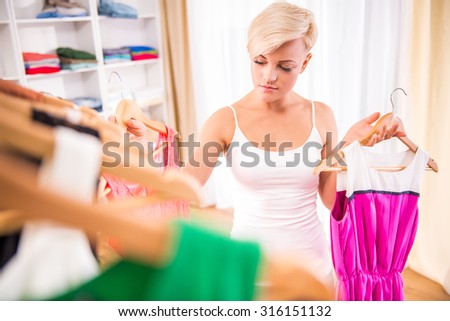 Young beautiful woman is choosing between two dress in the store.