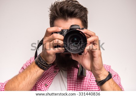 Young cheerful photographer with beard, while working in studio