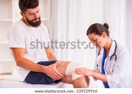 Injury leg. Young man with injured leg. Young woman doctor helps the patient