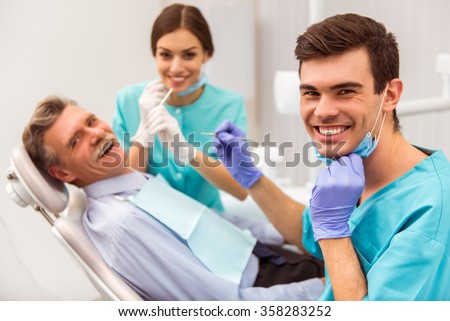 Young dentist and his assistant treating elderly man