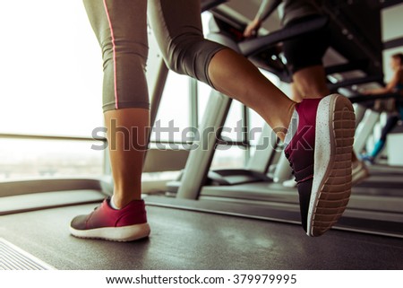 Legs of woman running on a treadmill in gym, close-up