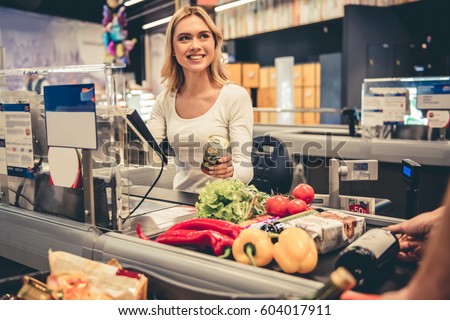 Beautiful young cashier is smiling while working at the supermarket