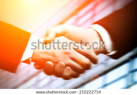 business hand shake and a office in background