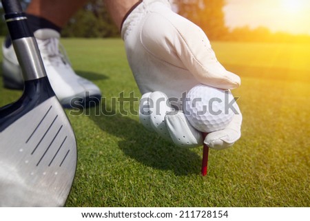 hand placing a tee with golf ball