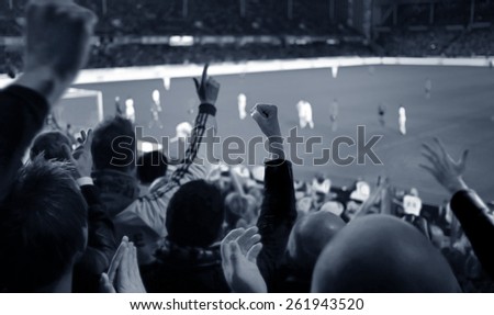Fans excited at a football game, selective focus on fans with hands raised