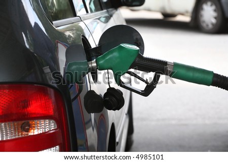 A service station gas nozzle in the fuel filling hole of a car. focus on the handle