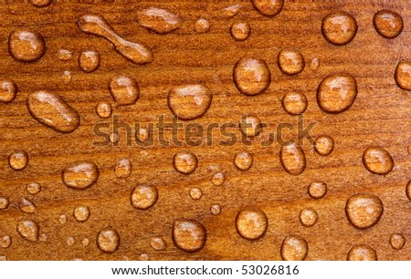 Waterdrops on red brown wood reflecting in the sun
