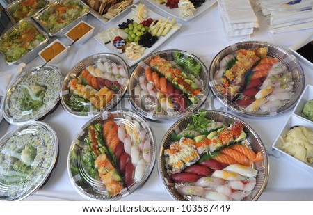 Sushi, sashimi, rolls on trays and cold snacks being prepared for a party on buffet table, catering