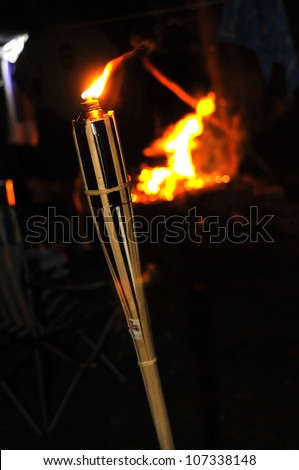 Camp fire and flame of a bamboo torch burning in the night.