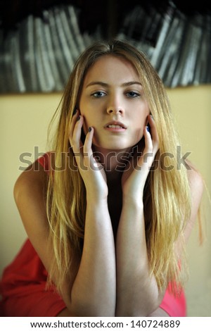 Portrait of young blond girl posing pretty at natural light from window