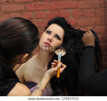 Make-up artist fixing blushes on model face during location photo shoots under Manhattan Bridge in NYC