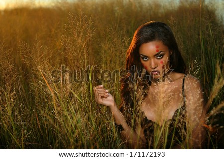 Beautiful african-american woman wearing black lingerie corset at the sunset at grass field
