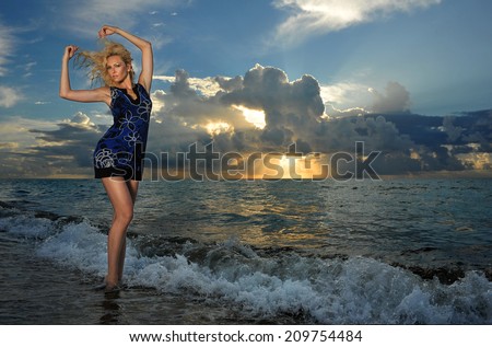 Model posing in beach dress at early morning sunrise over the ocean at tropical location
