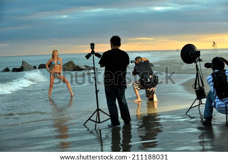Photographers and bikini model in summer photoshooting on the beach during sunset time.