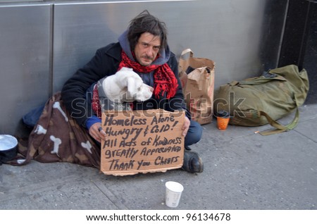 NEW YORK - FEBRUARY 25: A homeless man sitting on the street with a dog and asking for help February 25, 2012 in New York City.