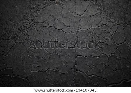 Cracked texture of dark asphalt wrinked from sun exposure