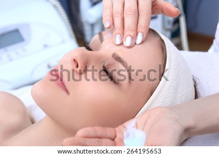 Beautician makes cleansing and exfoliating facial for beautiful girl. Beauty salon.