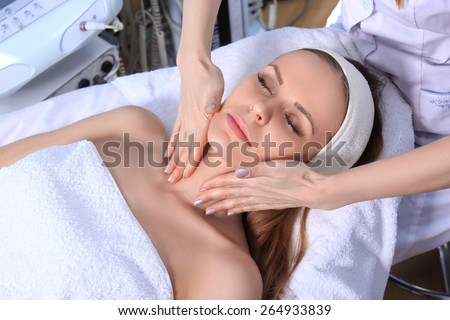 Young beautiful girl getting spa treatments. Doctor doing massage of the face.