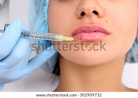 Beautiful girl on rejuvenation procedure in beauty clinic filler injection. Injections lips close up.