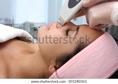 Woman receiving cleansing therapy with a professional ultrasonic equipment in cosmetology office