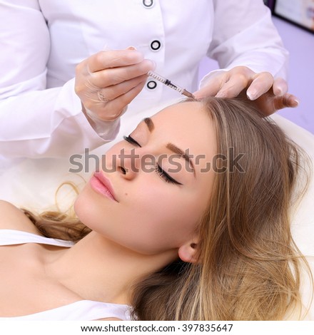 Female beautician makes injection of vitamins and minerals in the scalp. The concept of hair loss.
