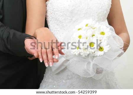 The groom holds the bride by the hand and a wedding bouquet