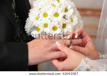 Bride puts wedding ring on groom\'s finger