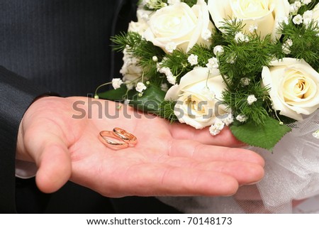 The groom show off his and the bride\'s wedding bands in the palm of his hand