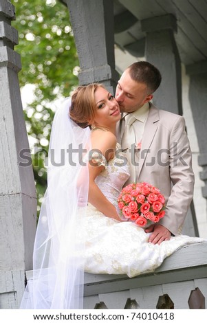 Young couple on a formal wedding photo. The groom kisses bride.