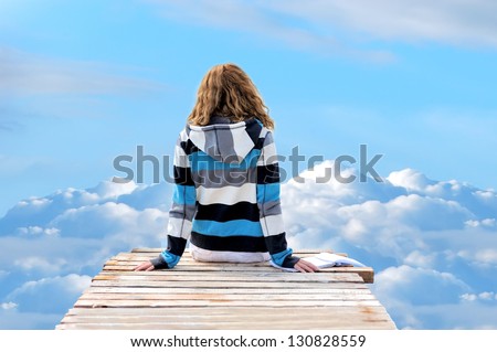 Young woman running across the clouds in the sky. Soul relaxation concept