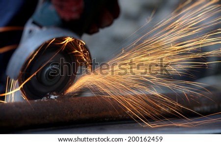 Worker cutting metal with grinder. Sparks while grinding iron