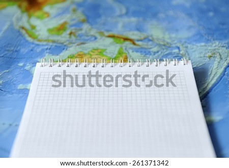 Notebook on a background map of the world. Traveling concept