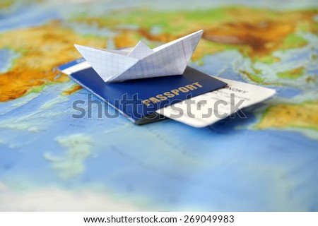 Paper boat, passport on a background map of the world. Traveling concept