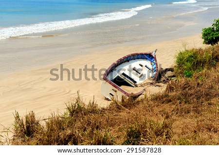 Old yacht stranded on a beach after storms in ocean