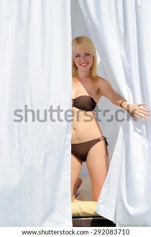 Sexy young woman relaxing in four-poster bed on beach