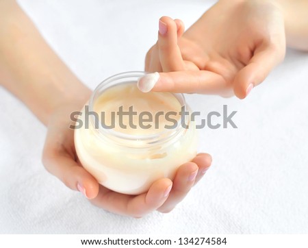 Beautiful woman hands with cream. Focus is on a finger