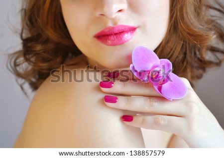 Beautiful woman with hand on shoulder and the flower of orchid