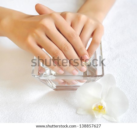 Woman hands in glass bowl with water on a white towel