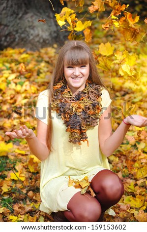 Young girl in an autumn park throws leaves