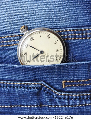 Old pocket watch in the pocket of blue jeans