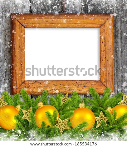 Old frame with gold christmas decoration baubles and pine on a snowbound wooden background